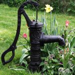 cast iron hand water pump installed on garden lawn for irrigation and decoration